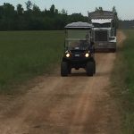 Small vehicles driving down dirt path on farm